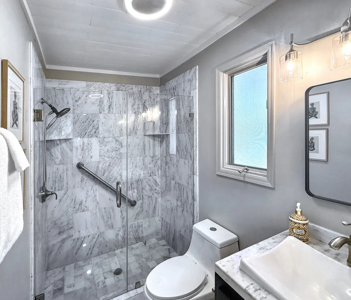 A modern, luxurious bathroom with a spacious marble shower, elegant vanity with sink, and decorative touches. The aesthetic is serene and spa-like, creating an environment perfect for relaxation and personal care after a day of adventure.