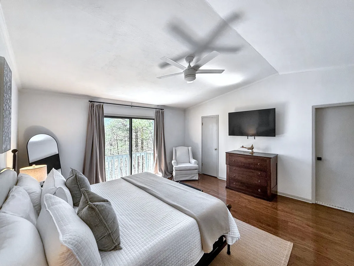 A serene bedroom featuring a large bed beside an armchair and a window that opens up to nature. Ample light and soothing colors create a restful retreat, while the window view invites a sense of connection to the outdoors, mirroring the rejuvenating experiences described in the text.