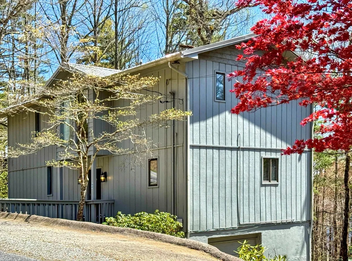 Showcasing the home's modern architecture nestled among colorful foliage and natural landscaping, the image conveys an inviting and serene atmosphere. The red tree and clear landscaping paths evoke the seasonal charm and accessibility that comes with living near downtown.